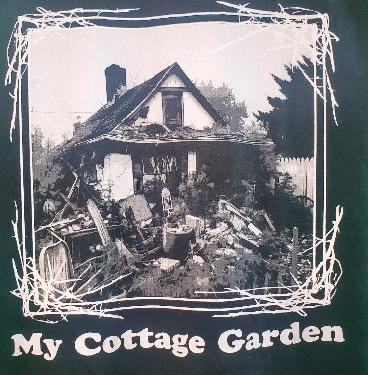Close-up of 'My Cottage Garden' T-shirt graphic showing a haunted house scene within a thorned frame, blending decay with nature
