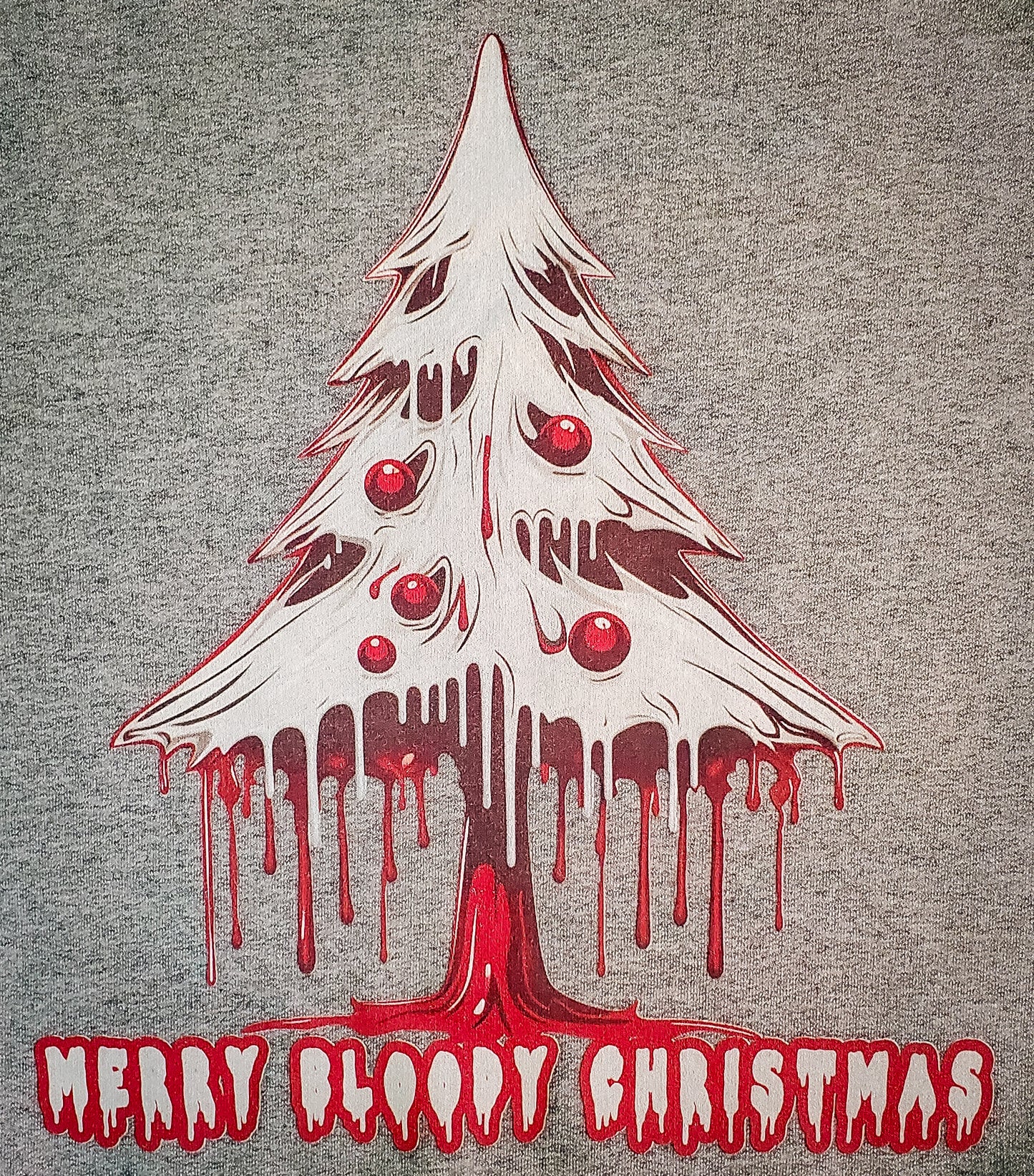 Close-up of a gray sweater featuring a spooky dripping Christmas tree graphic with 'Merry Bloody Christmas' in a scary red font.