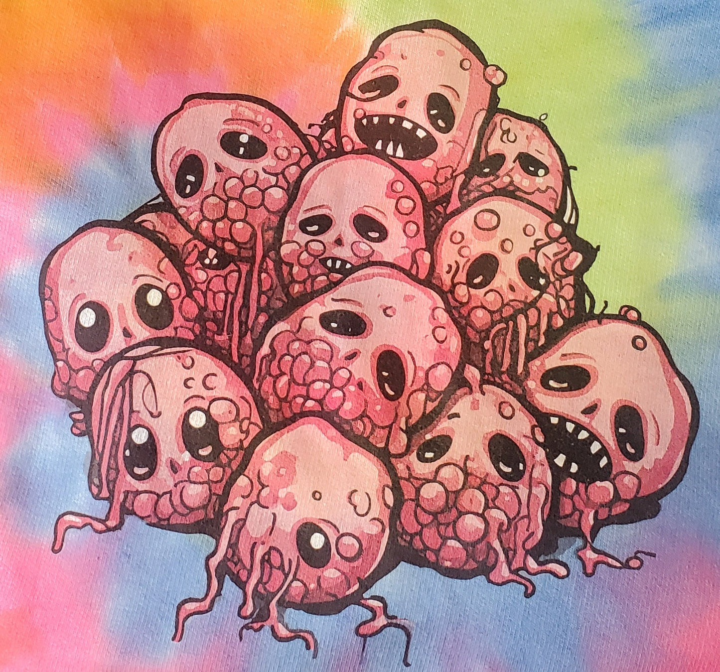A close-up of the graphic on the tie-dye sweatshirt featuring a group of cartoon raspberries with expressive faces and pink details. The background showcases the vibrant tie-dye pattern of the sweatshirt.