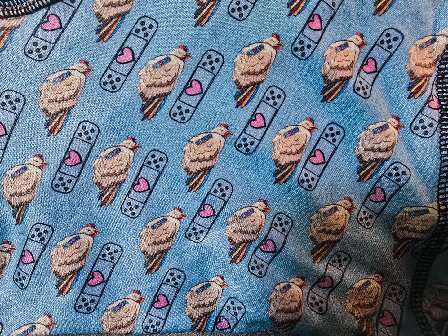 A close-up of the playful pattern on light blue boxer briefs, showcasing detailed illustrations of chickens and bandaids with pink hearts, highlighting the intricate and fun design