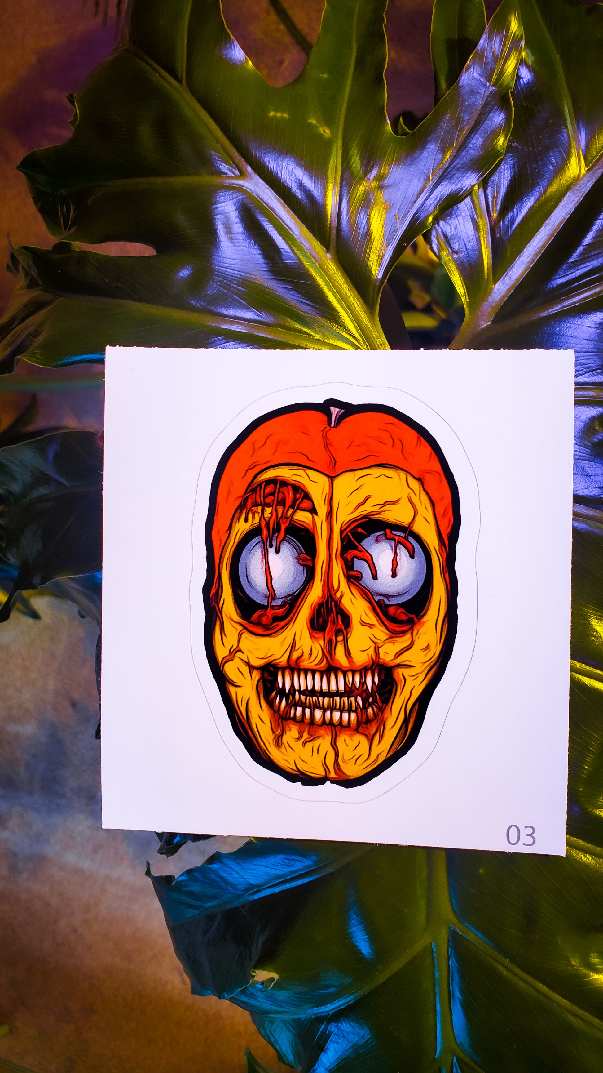 Eerie passion fruit skull sticker poised against the vibrant leaves of an indoor plant.