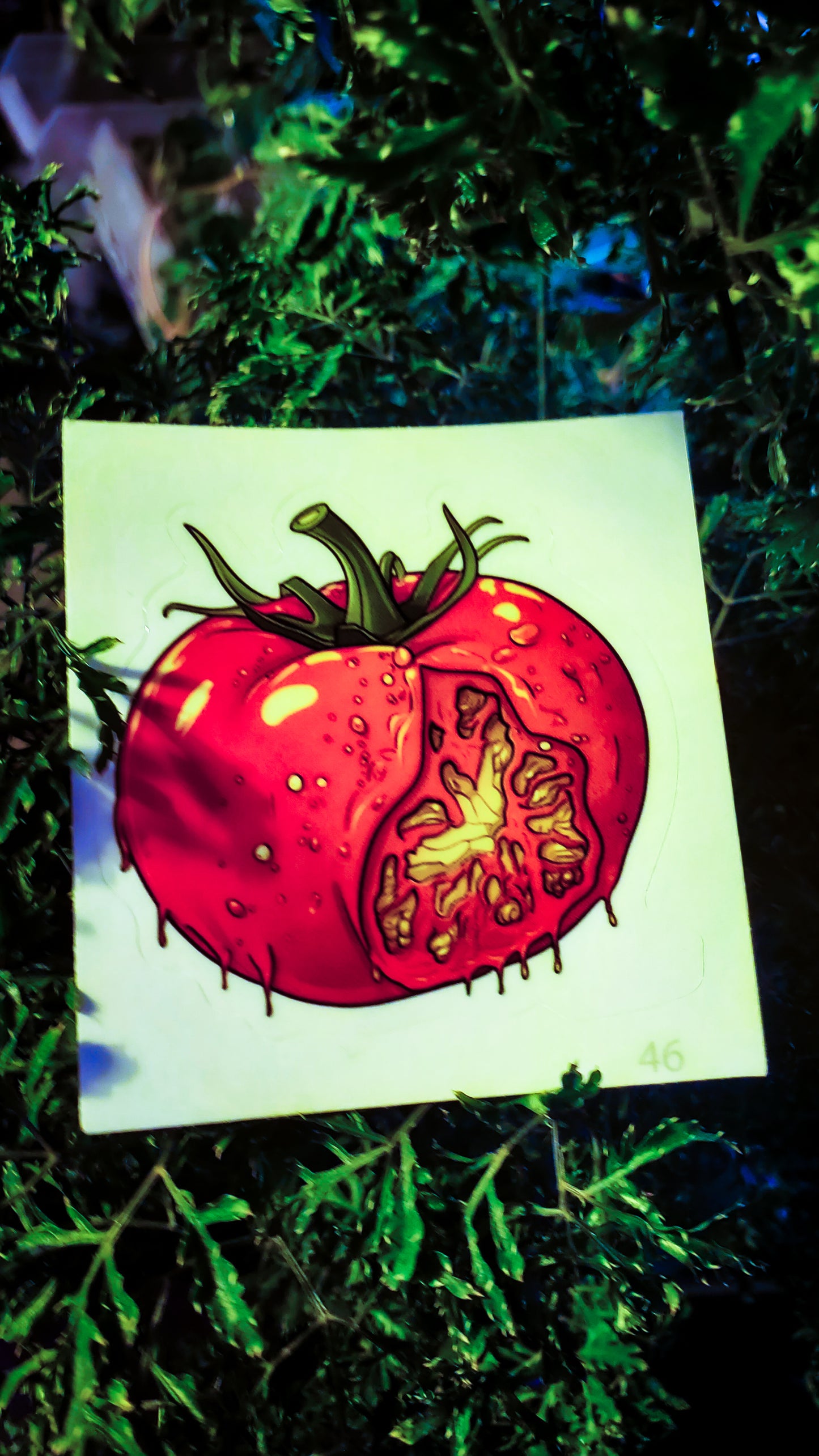 Spooky tomato sticker against a dark, leafy plant, evoking a moody ambiance.