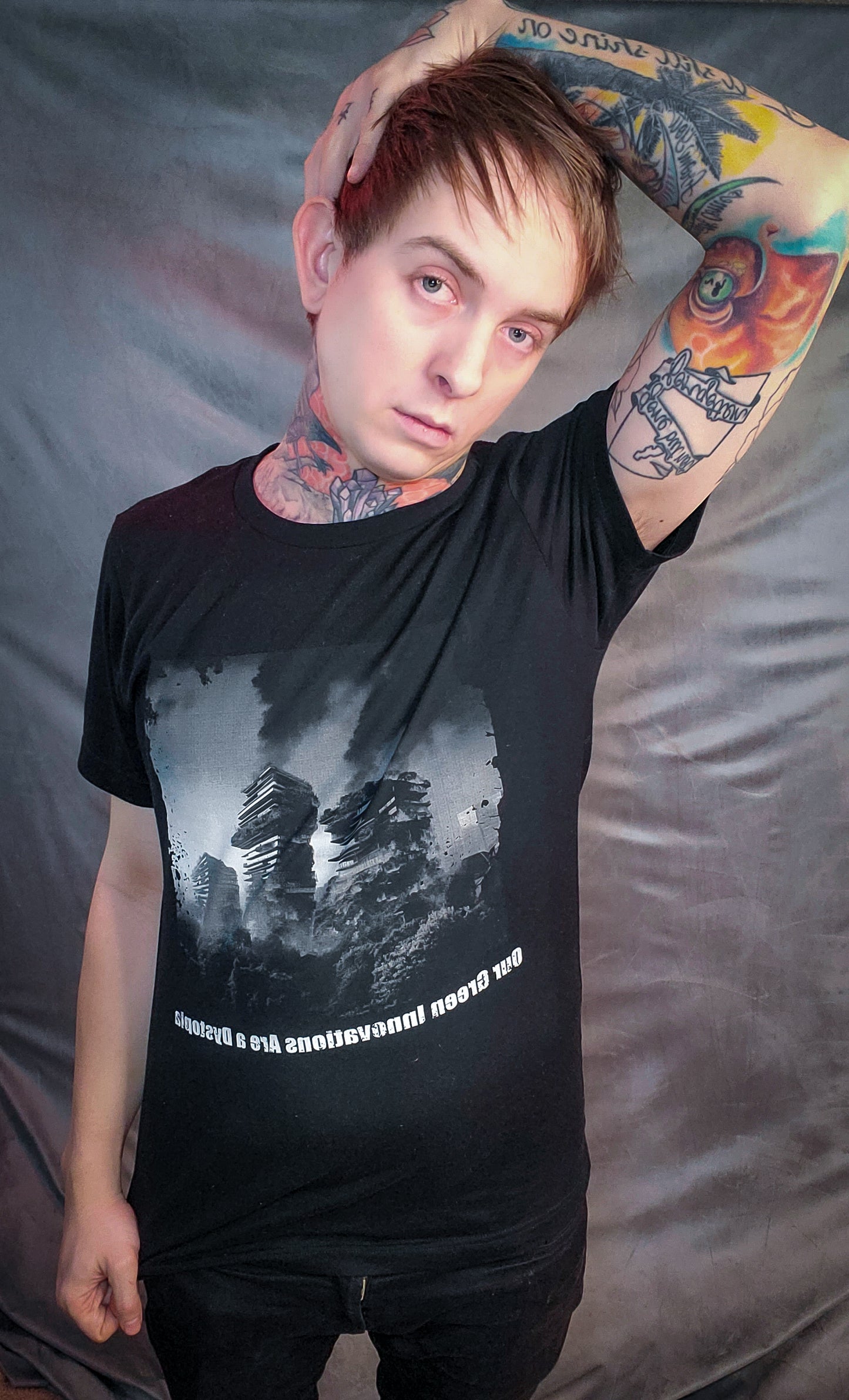 Edgy black tee with a dystopian theme, featuring a burning high-rise forest design, modeled by a person with bold tattoos, capturing Mortal Greenworks' unique aesthetic.