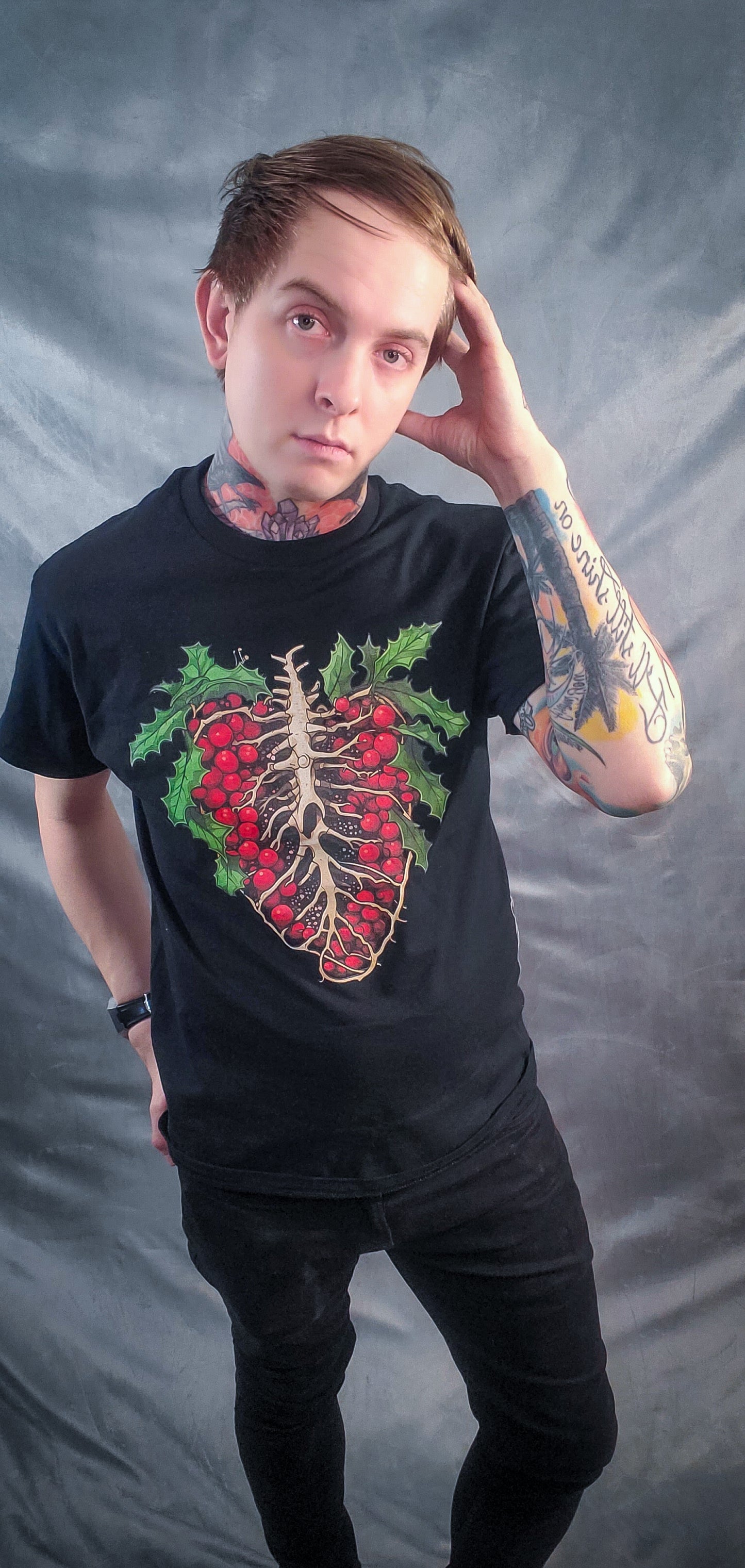 Person in a black t-shirt with a vibrant holly ribcage design, pairing holiday elements with an anatomical twist