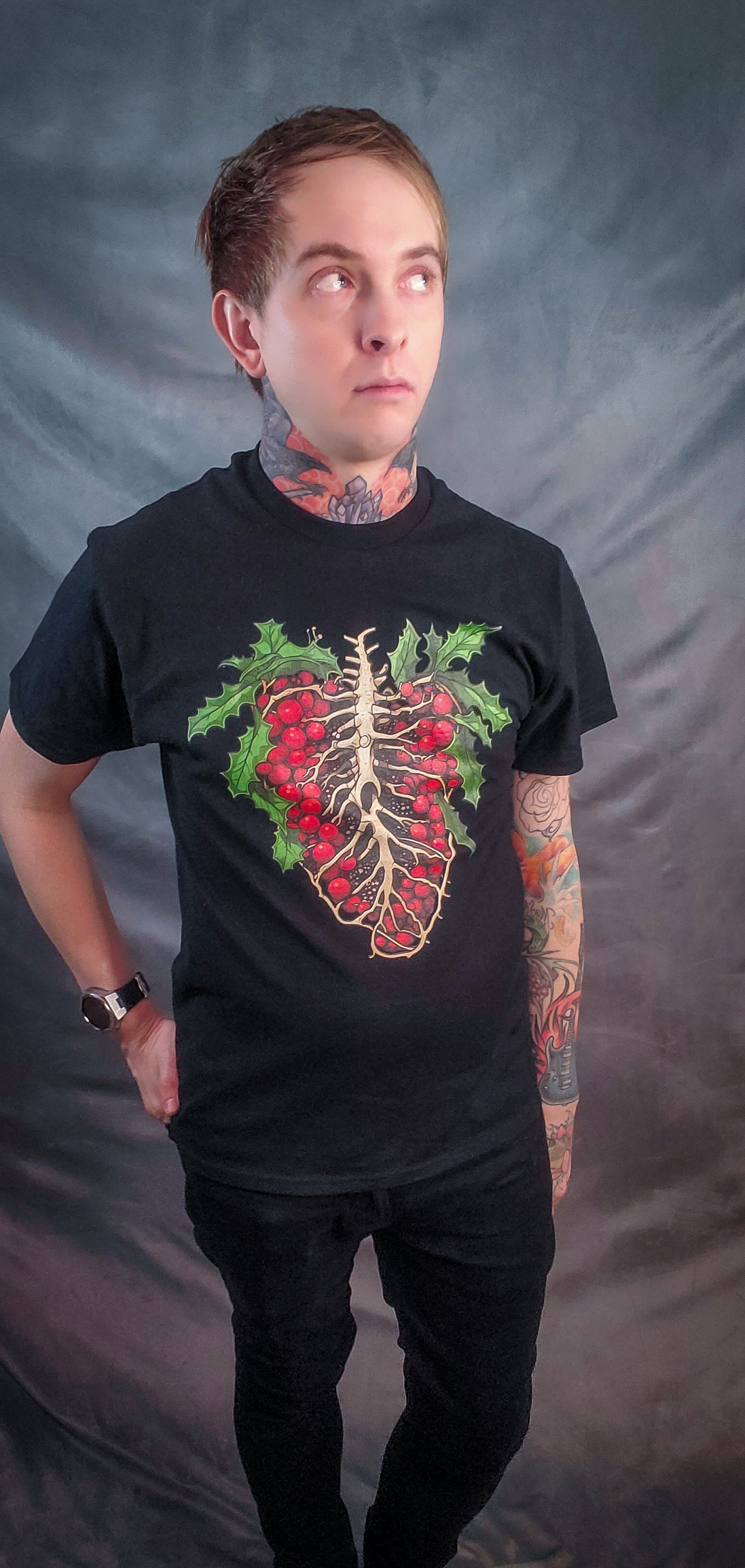 Individual posing in a black tee featuring a holly ribcage graphic, merging Christmas vibes with a skeletal structure