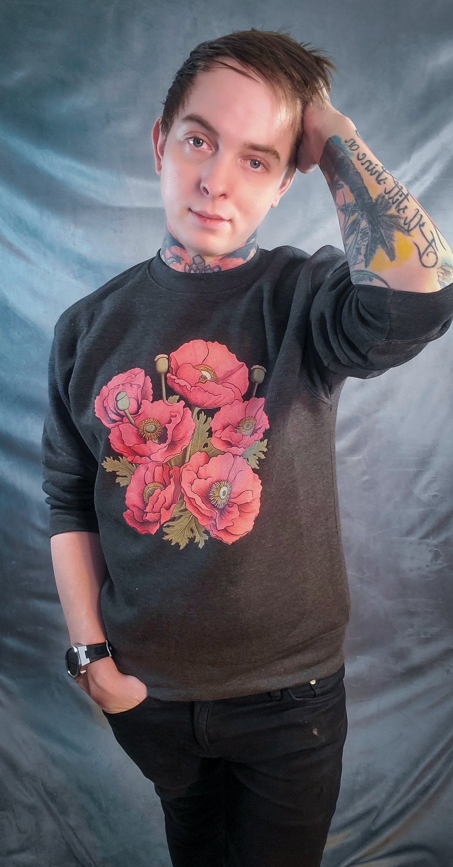 Person posing with hand on head, showcasing red eyeball poppy design on a dark sweatshirt.