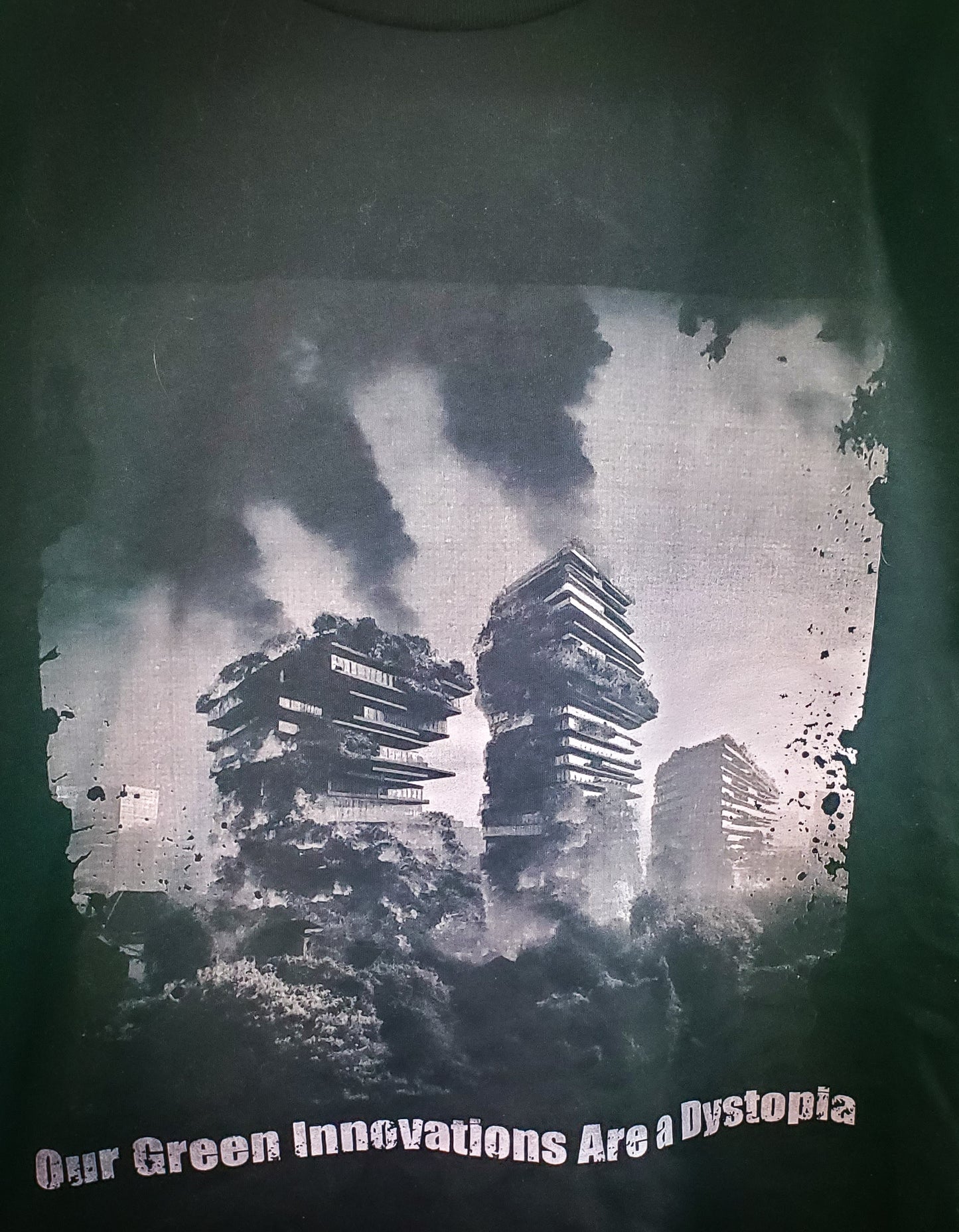 Graphic close-up on a black T-shirt depicting eco-dystopian imagery of tree-covered skyscrapers ablaze, reflecting a dark environmentalist message.