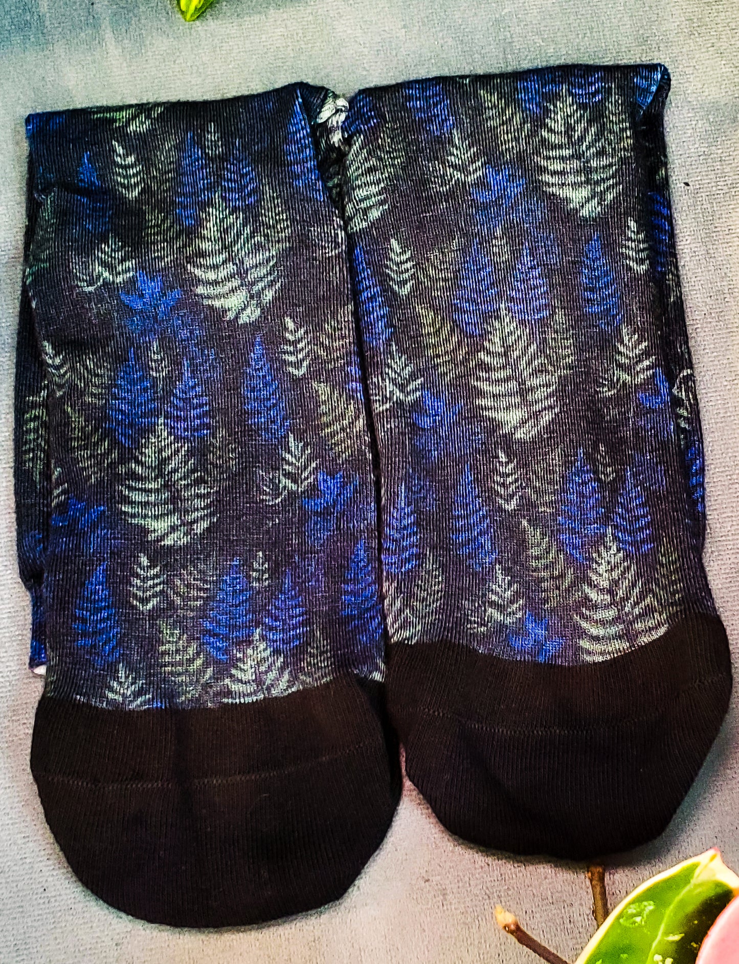 Close-up of dark socks with a mystical fern motif, contrasting with the dark fabric background.