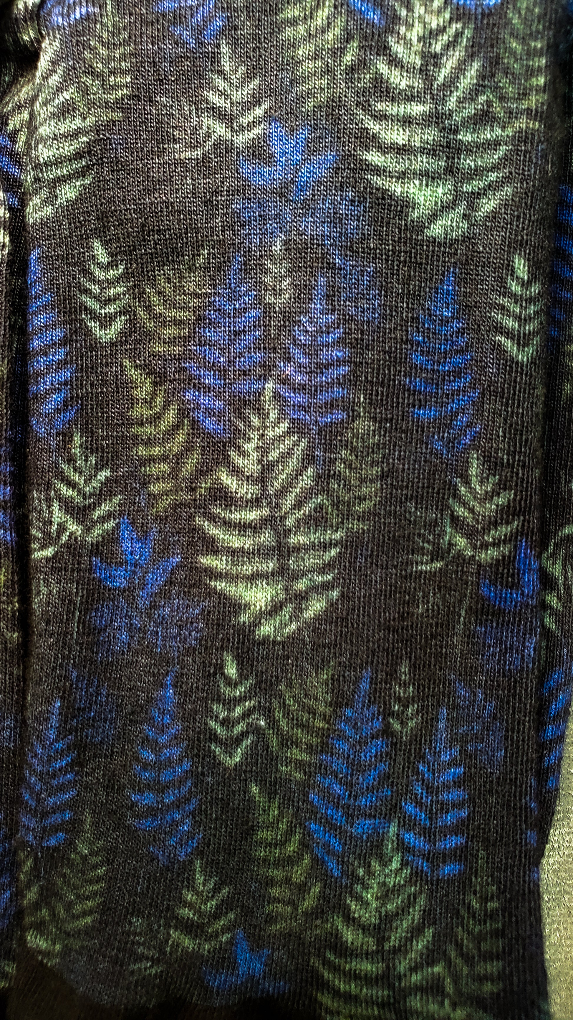 Intricate fern patterns adorn these socks, casting a haunting glow against the dark material