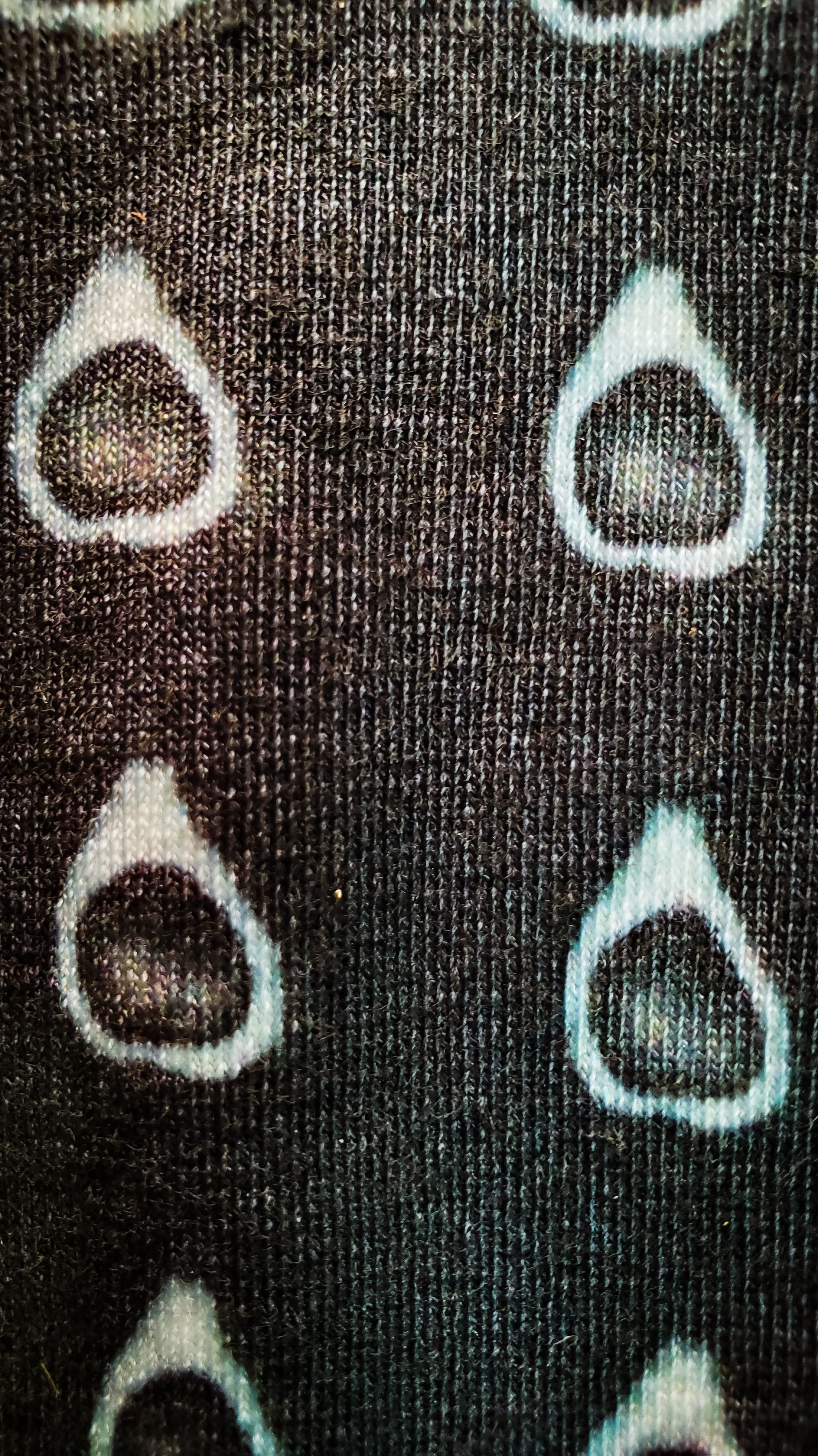 Close-up of black socks adorned with an eerie avocado design, merging the everyday with the supernatural, ideal for those with a dark sense of style.