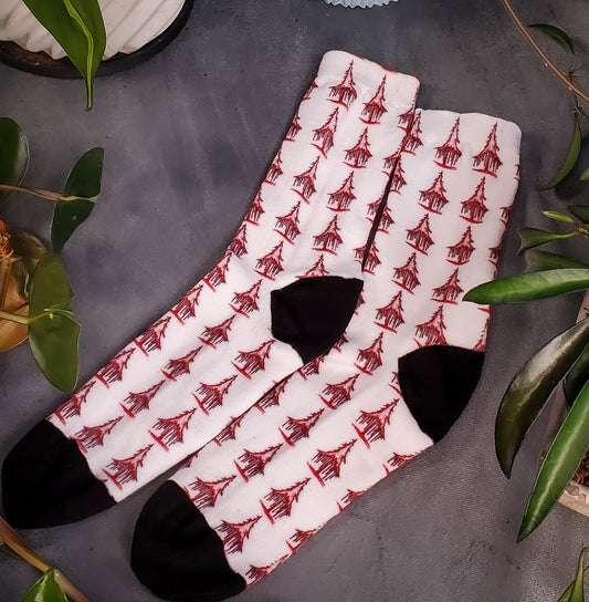 Off-white socks featuring haunting red solstice trees, set against a backdrop of lush greenery.