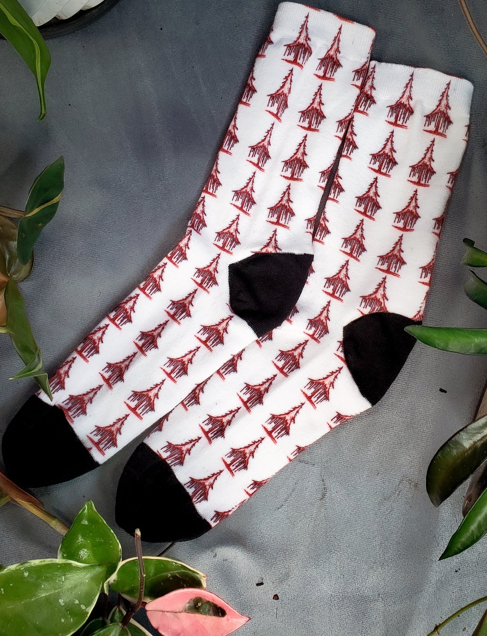 Crisp white socks with a chilling pattern of bleeding red trees among vibrant leaves on gray.