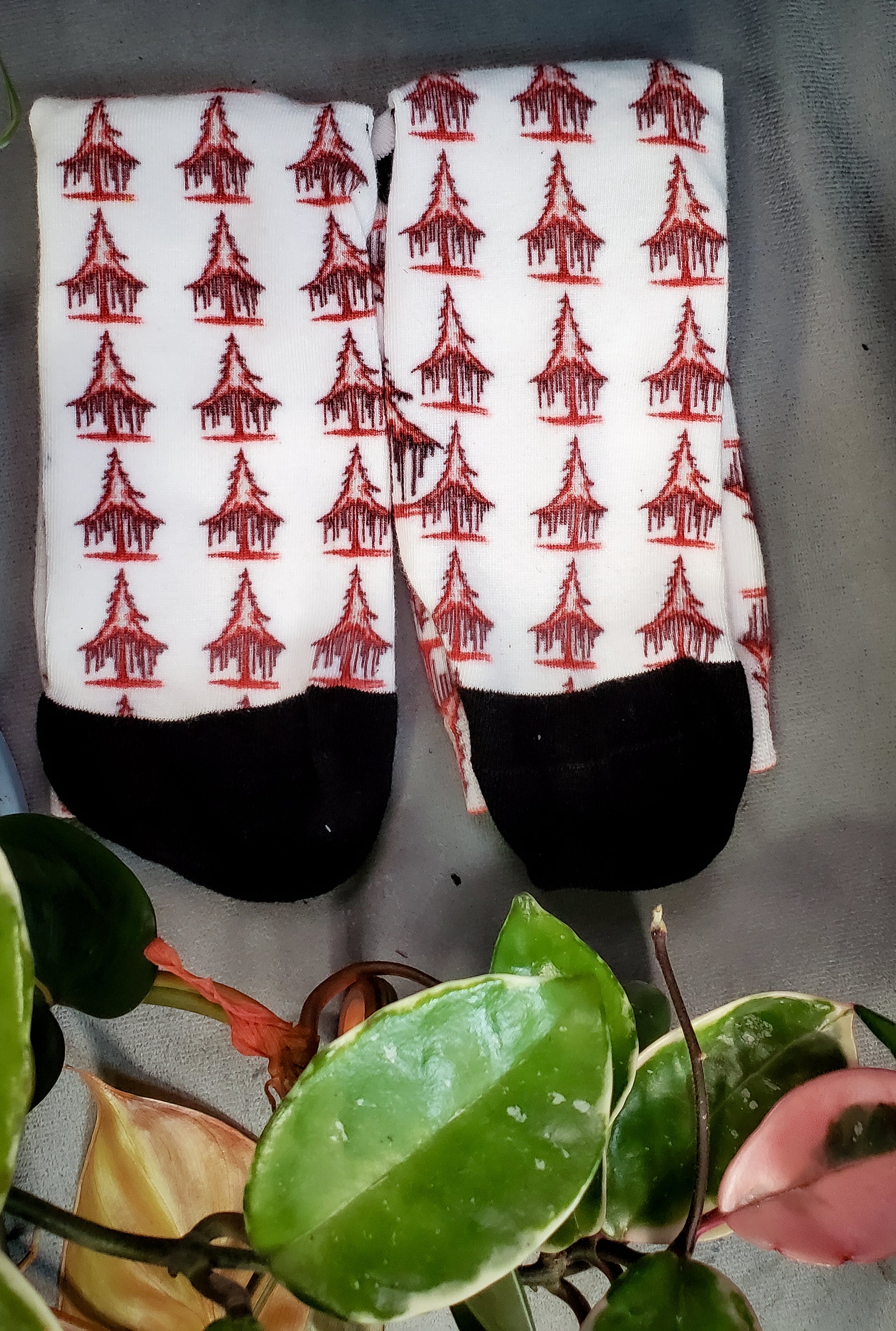 Socks with a stark white base and eerie red solstice trees, nestled among green and pink leaves.