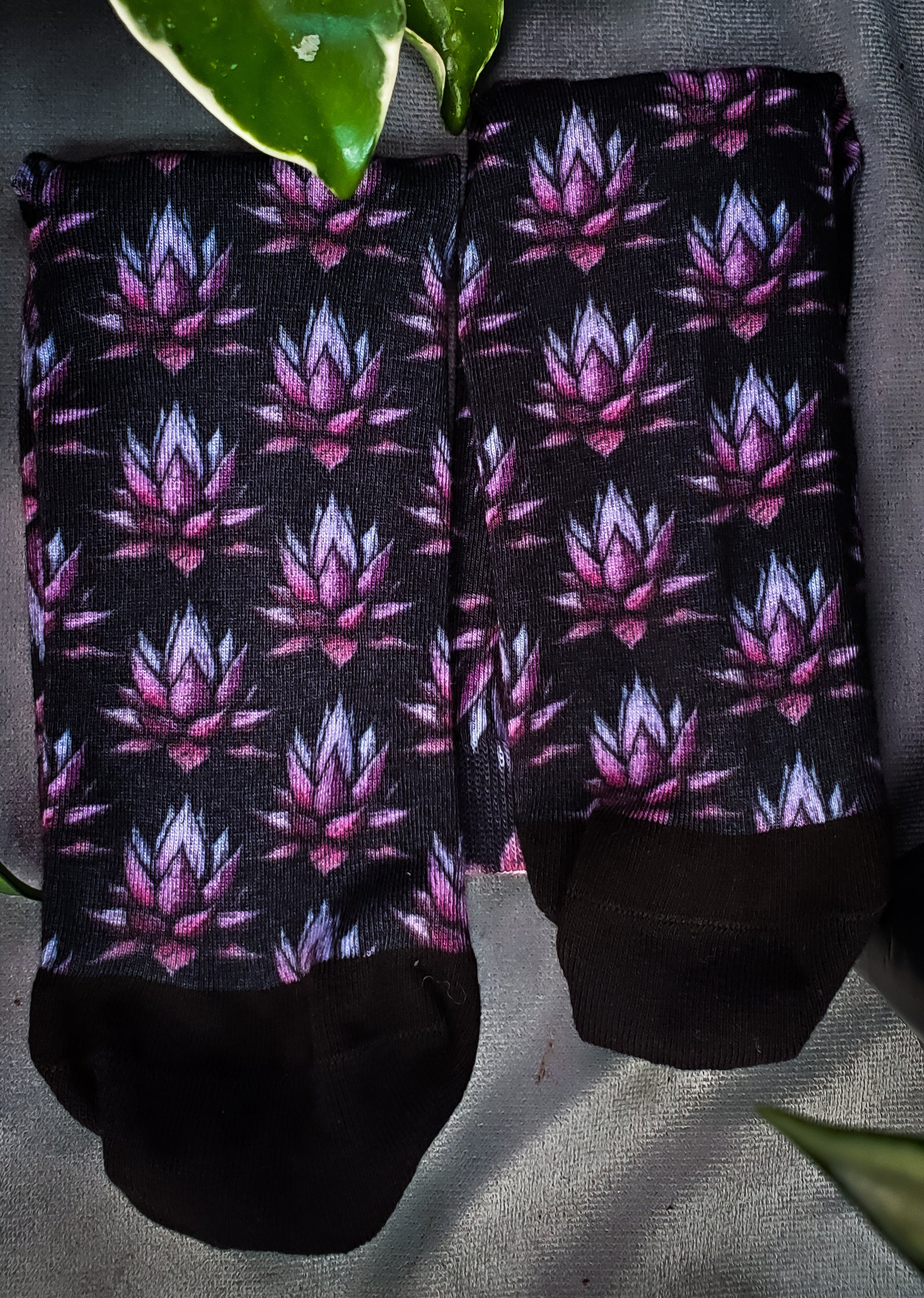 Gothic-inspired socks with vivid purple agave designs, resting among a bed of leaves.