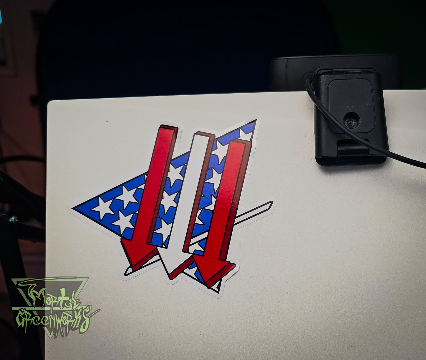 Three red, white, and blue arrows on the back of a white monitor, next to a webcam.