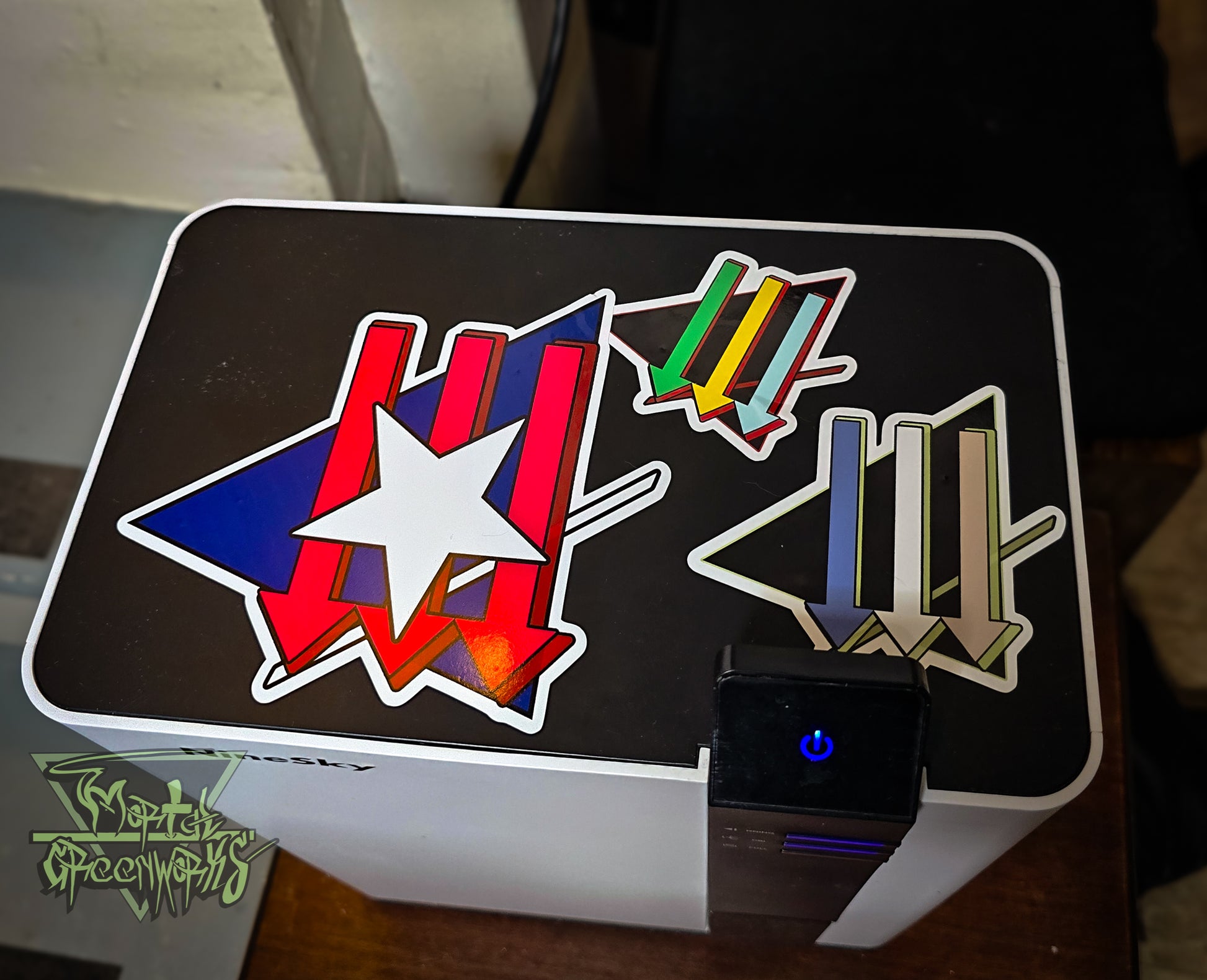 Overhead shot of three climate front stickers on a white Ninskey dehumidifier. The Stickers are a colorful assortment of white, blue, red, green, and gold. 
