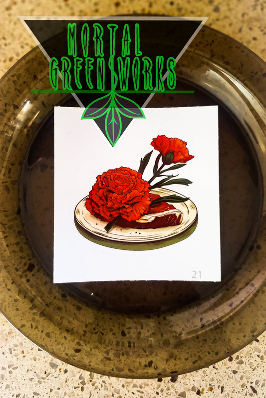 Sticker showcasing a red carnation on a raw steak, positioned on a kitchen counter with 'Mortal Greenworks' branding above.