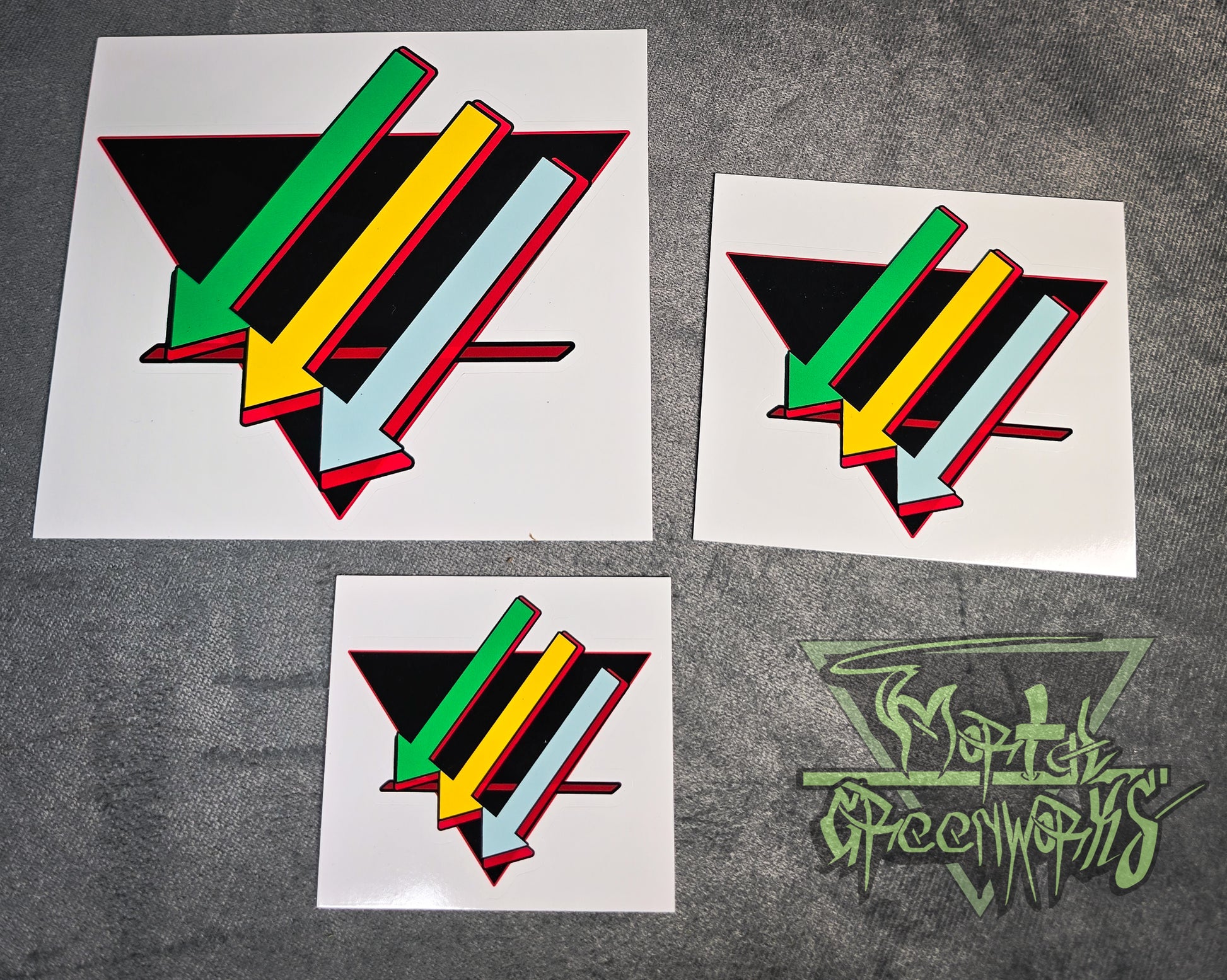 Photo of the three stickers with the Sonoran color scheme from 3x3" 4x4" and 6x".  Set on a contrasting grey table cloth