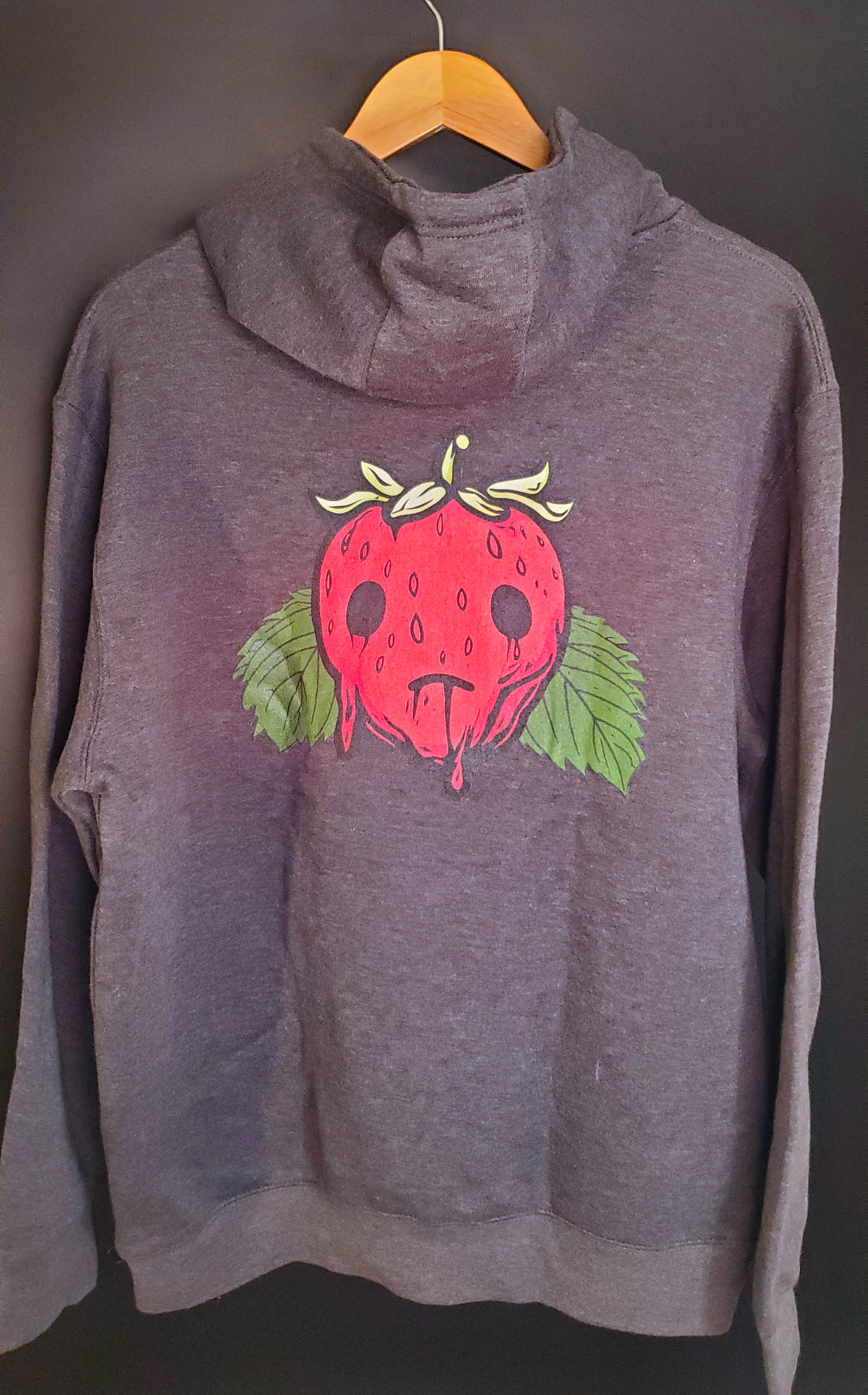 The back of a gray hoodie with a red strawberry graphic sits on a hanger against a dark background