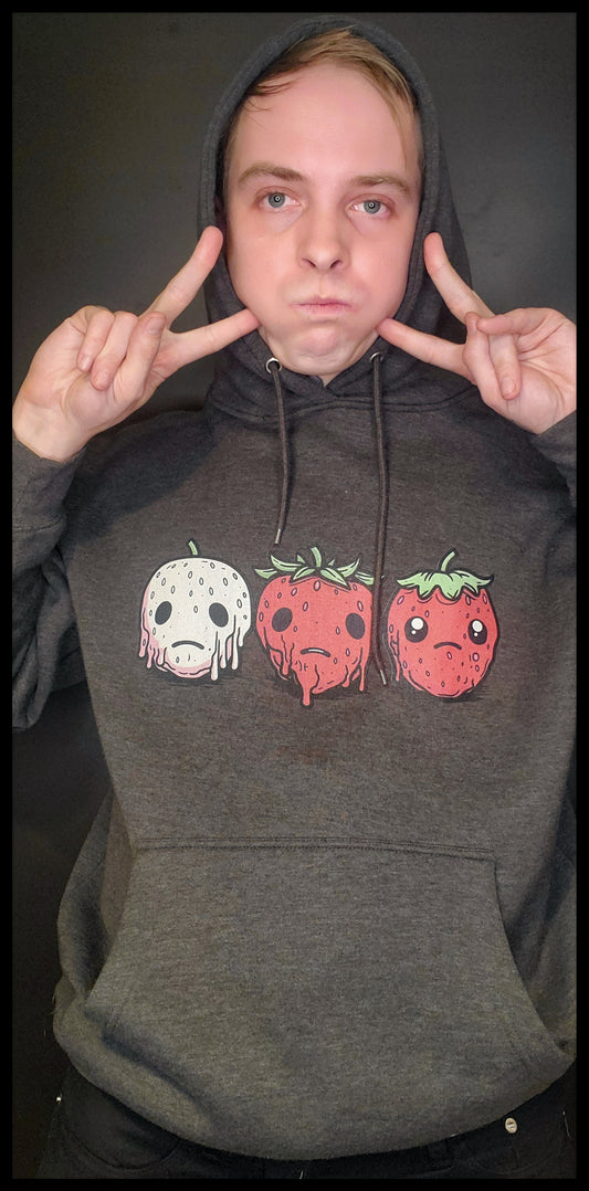 Front of Sad Strawberry Hoodie, Three frowning, melting strawaberries shown, Charcoal Grey, white male model in studio funny shot