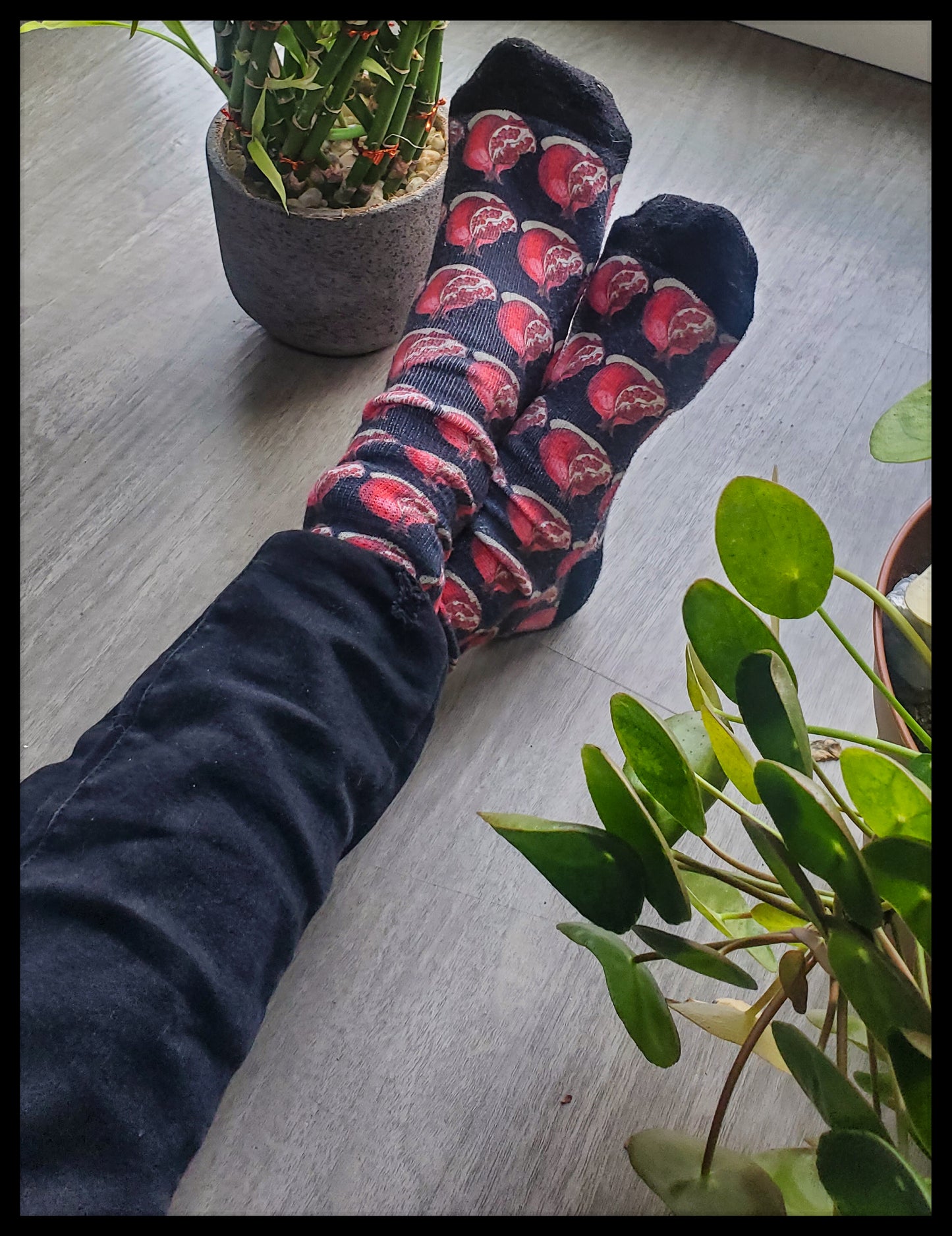 The socks showcase a repeated pattern of stylized red pomegranates on a contrasting dark background, creating an eye-catching design.
