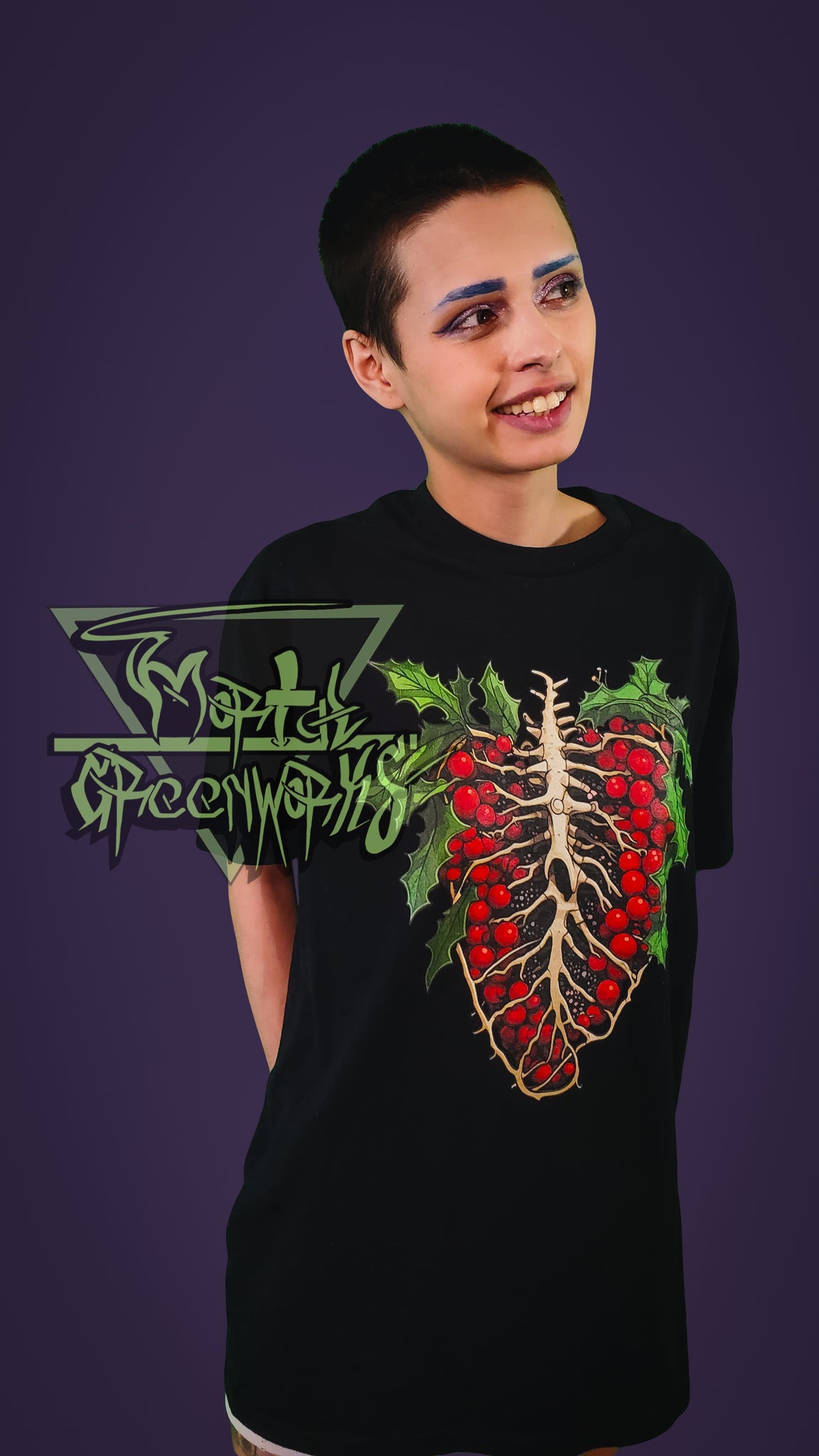 A Person wearing a black t-shirt with a red and green design of a skeletal ribcage with holly growing around it on a purple background