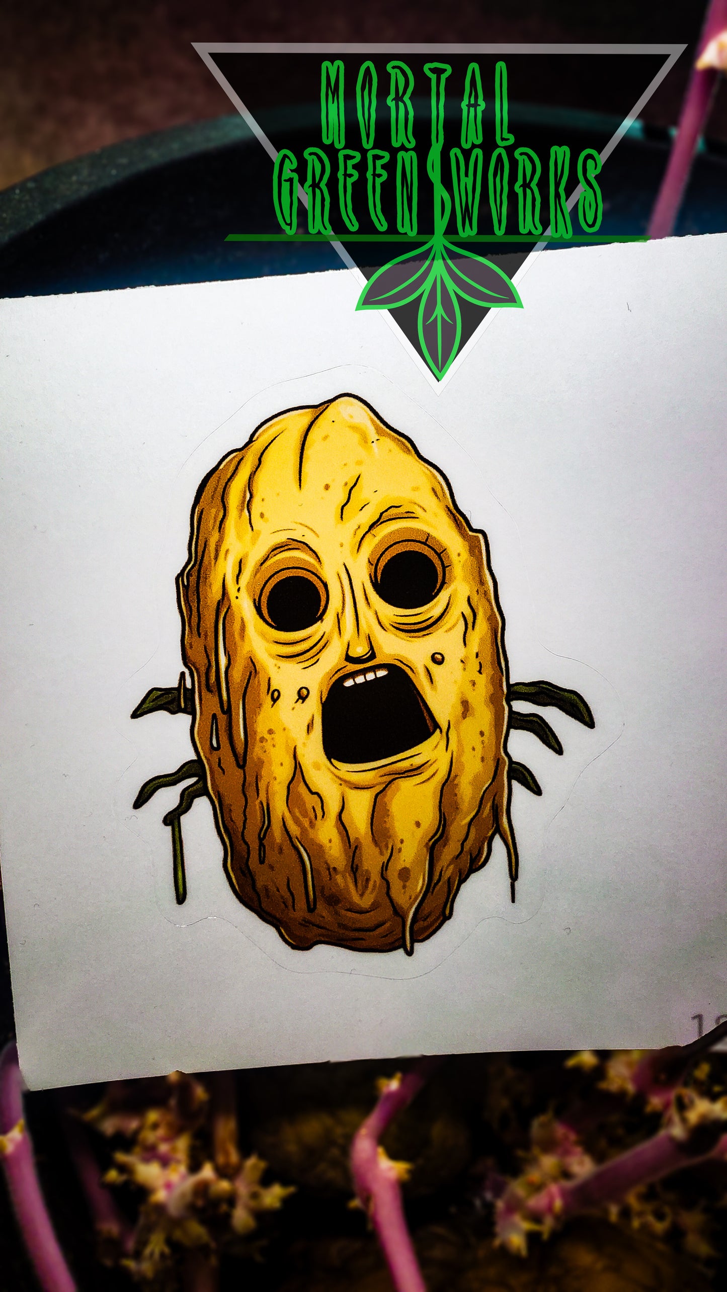 A sticker with a terrified potato face against a potato tuber backdrop and 'Mortal Greenworks' logo.