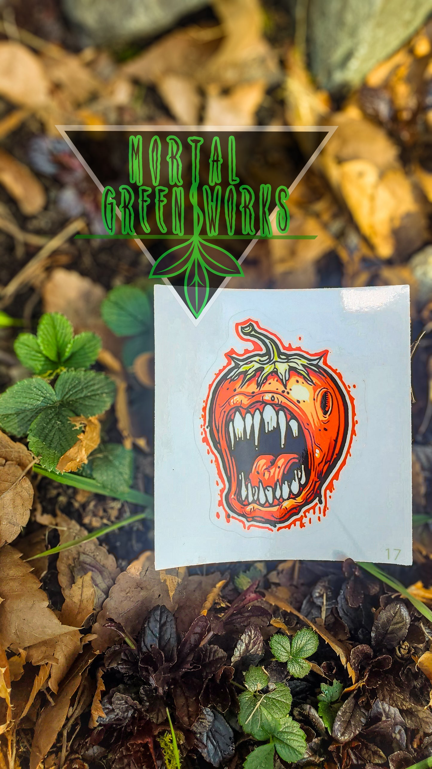 The 'Wild Strawberry, Horror Fruit' sticker atop soil, surrounded by foliage and 'Mortal Greenworks' branding.