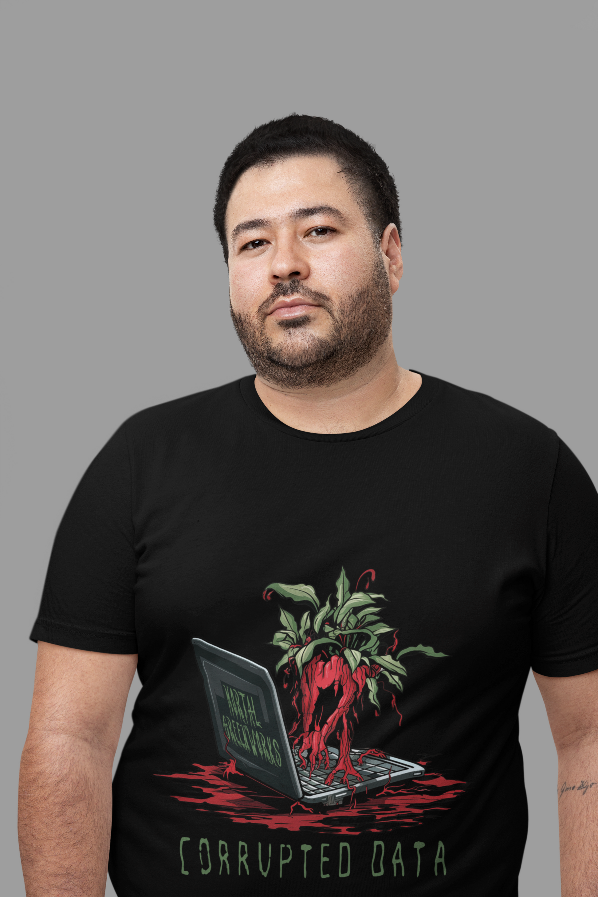 Man in black t-shirt with "corrupted data" and a graphic of a plant with red roots intertwined with a laptop, on a grey background.