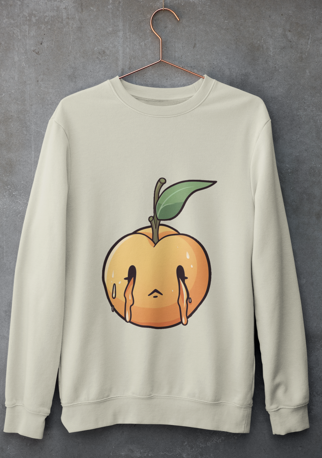 Cream sweatshirt with a melancholic cartoon peach character with a single green leaf.